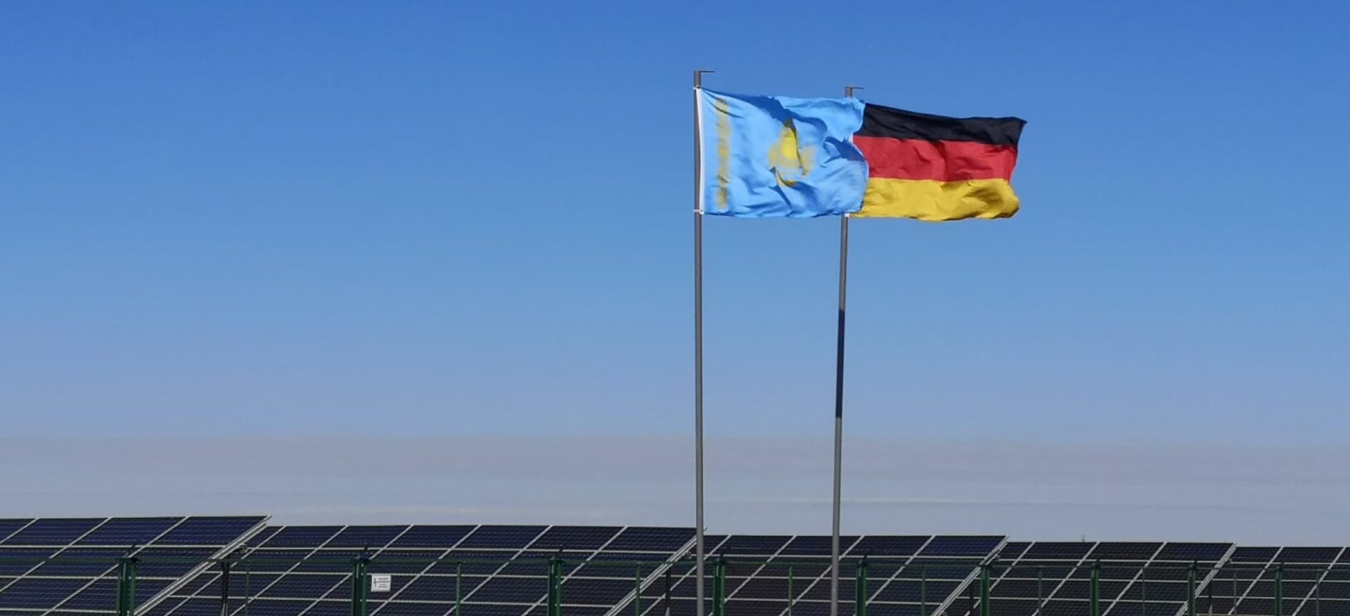 Die Flagge von Kasachstan und von Deutschland vor Solarmodulen