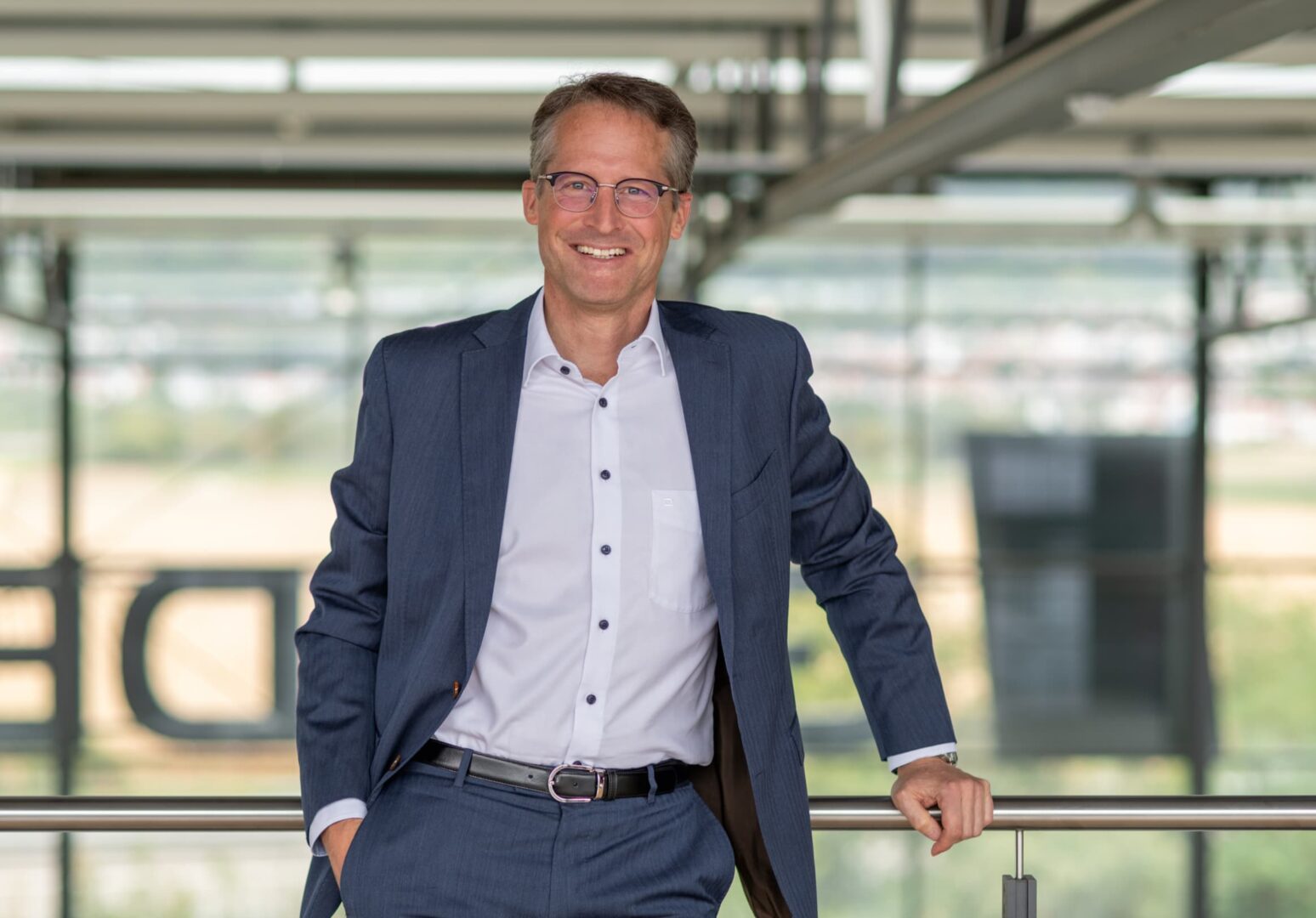 Ein Portrait von Joachim Goldbeck, CEO von GOLDBECK SOLAR. Er lehnt an einem Geländer und lächelt in die Kamera.