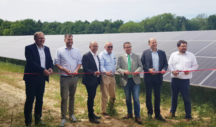 Sieben Männer durchschneiden das rote Band, mit dem der Solarpark Roigheim offiziell eingeweiht wird.