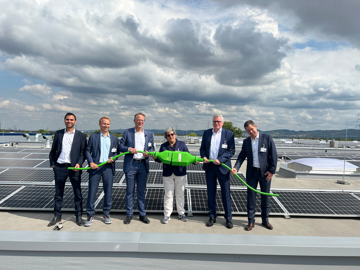 Ein Gruppenbild der Verantwortlichen bei der Einweihung des Solardaches Ladenburg. Sie halten einen großen grünen Stecker.